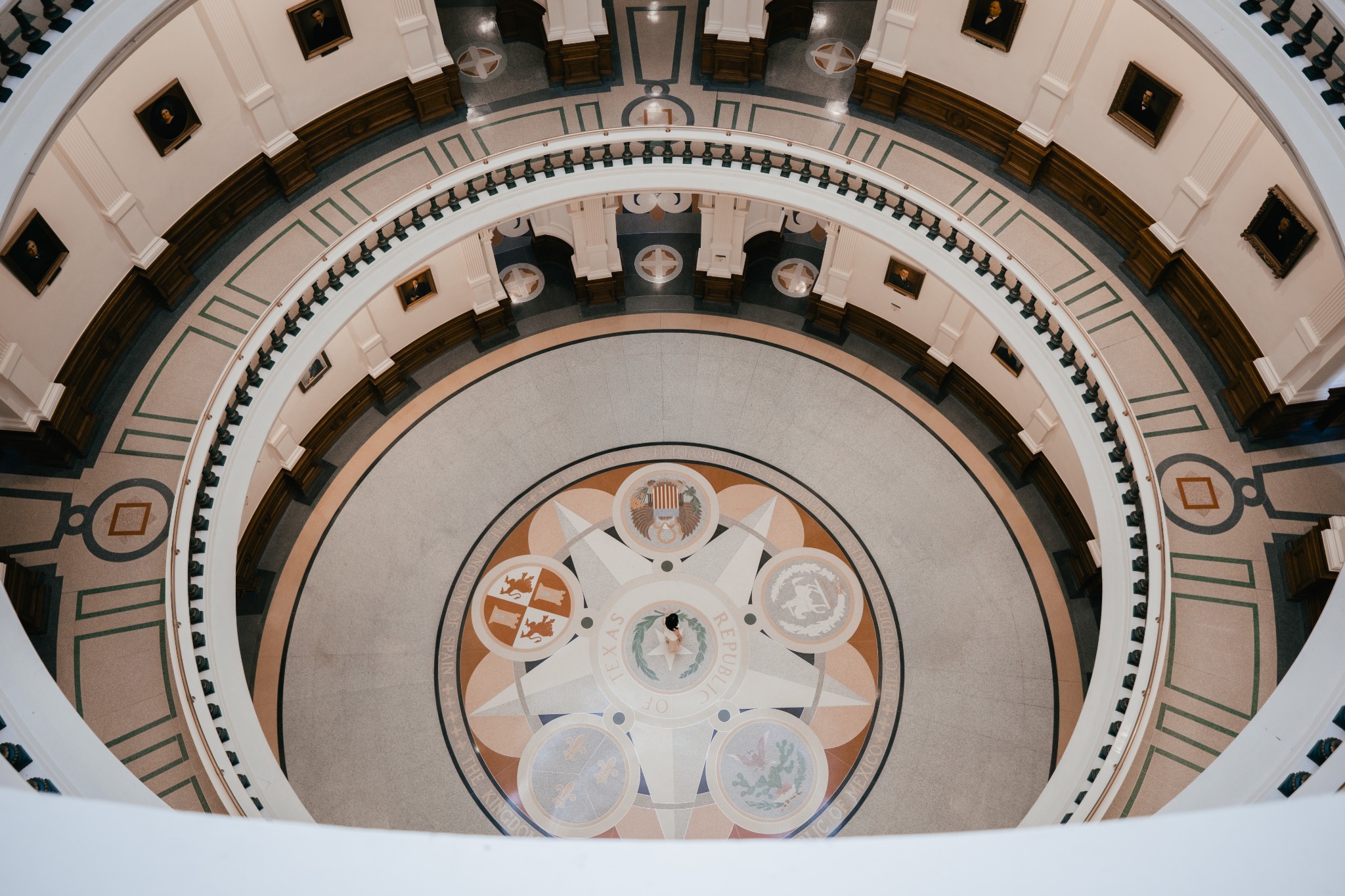 An overhead view through concentric rotunda balconies toward a patterned circular floor