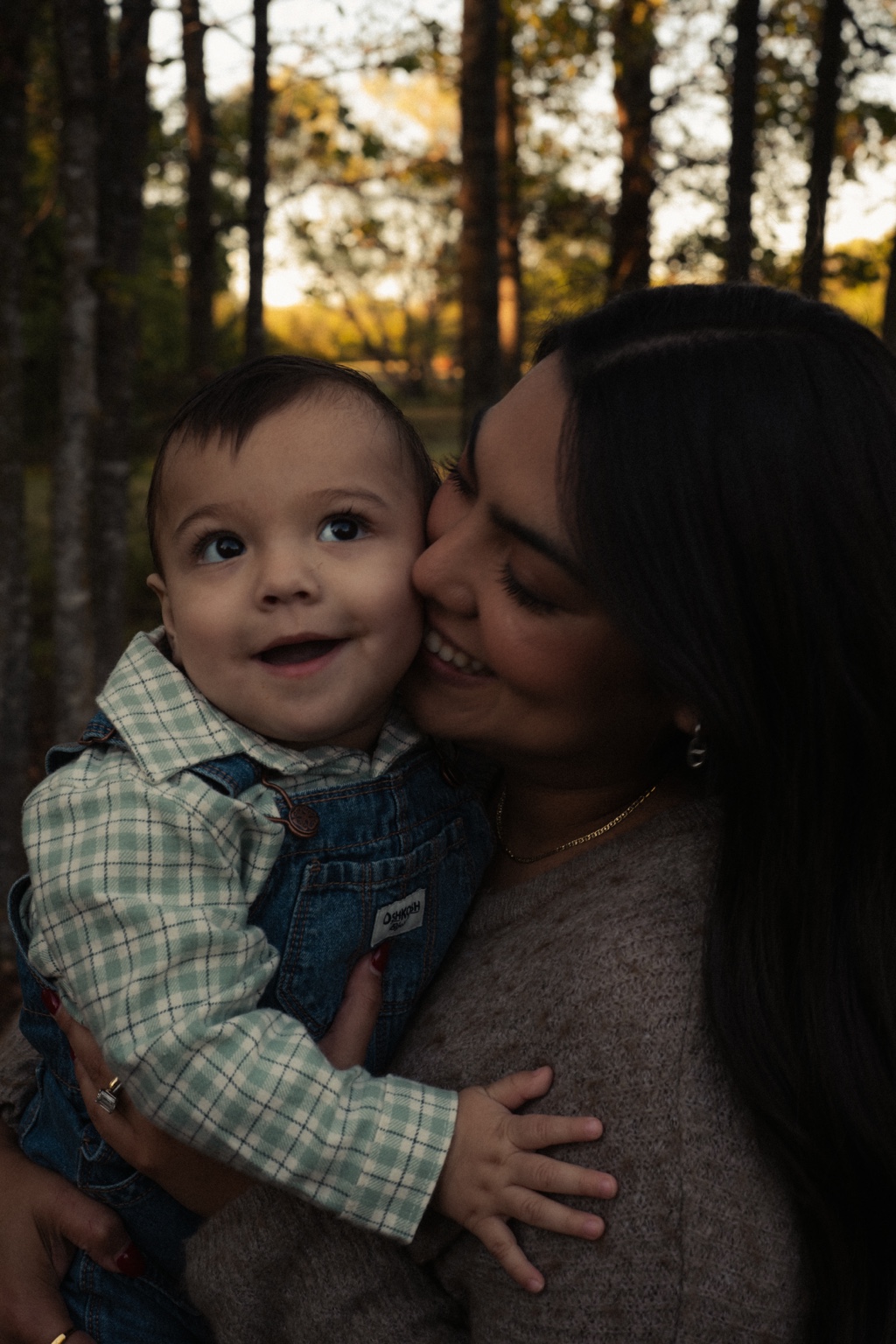 A mother kissing her smiling child outdoors