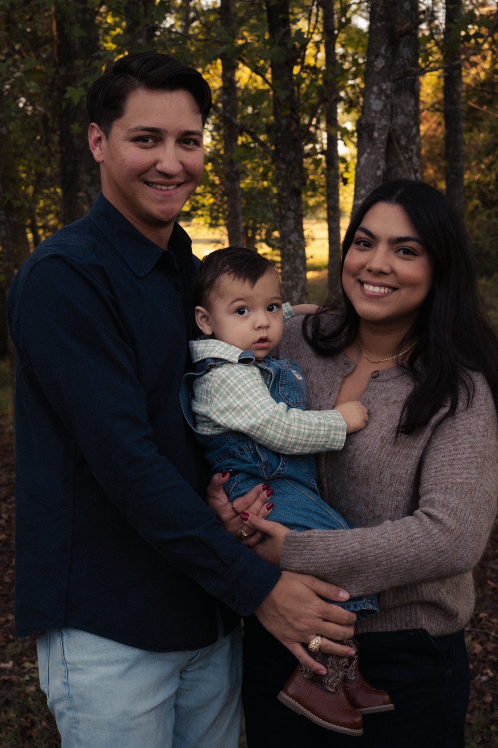 Parents holding their young child among the trees
