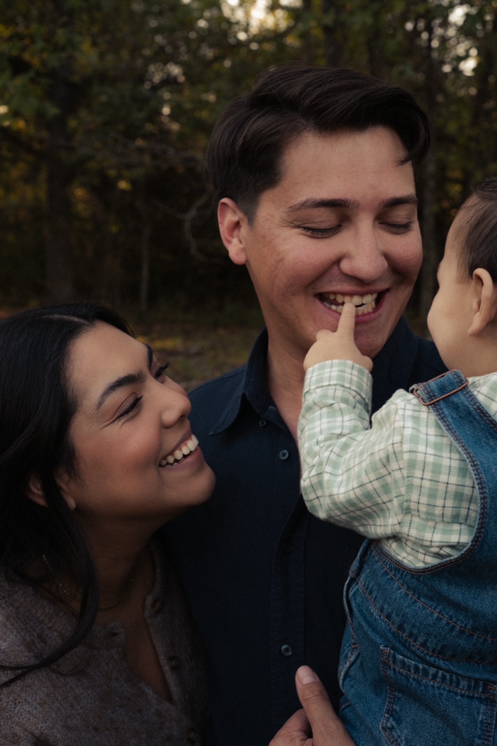 A family laughing as their child reaches toward his father’s face
