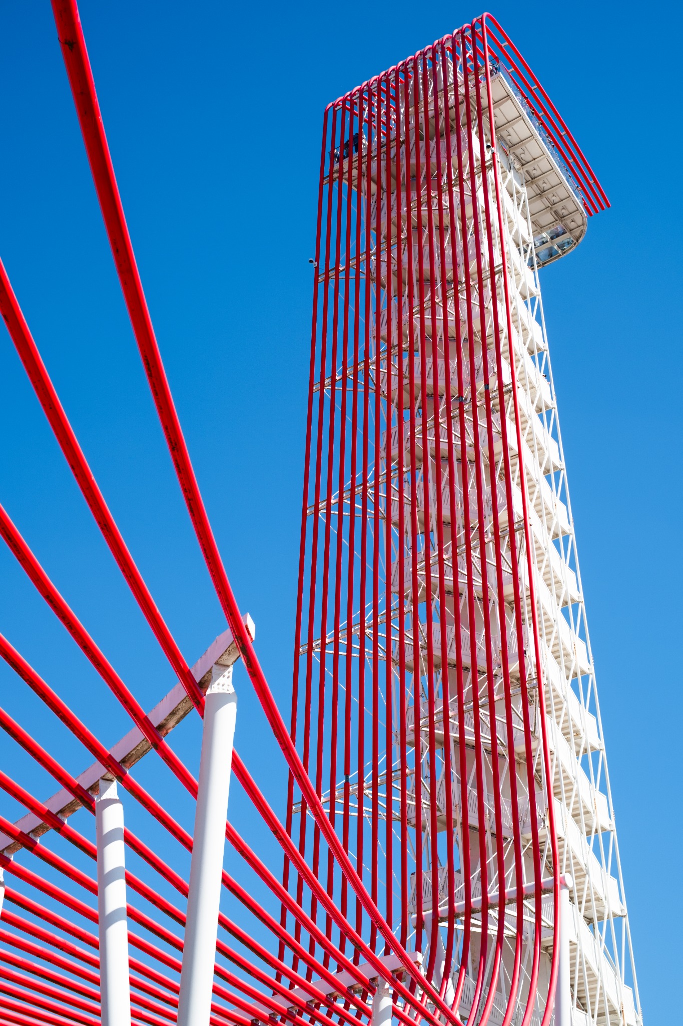 Red rails and a white observation tower rising against a clear blue sky