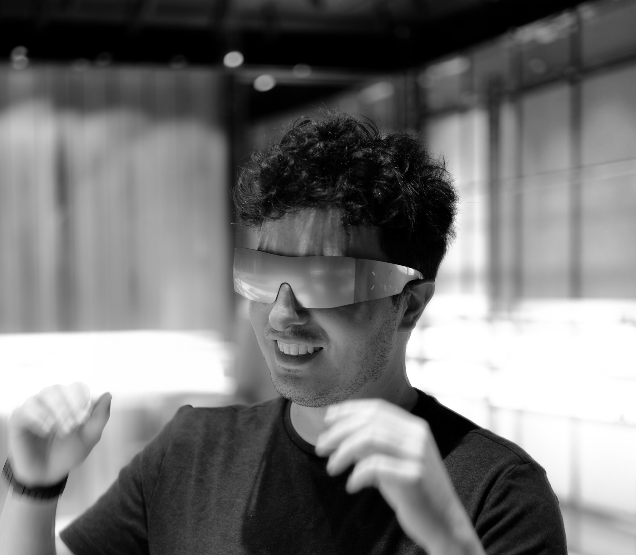 Black-and-white portrait of a smiling man wearing wide reflective sunglasses